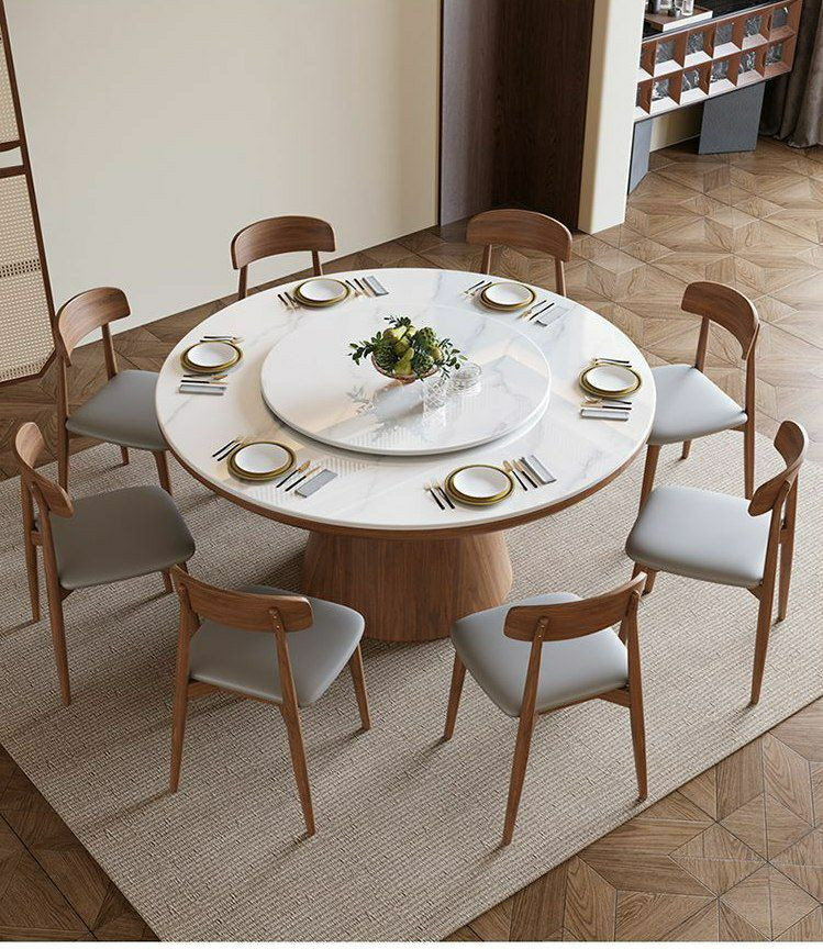 Table à manger ronde moderne en bois avec un plateau en pierre frittée et un plateau tournant central (type Lazy Susan), accompagnée de huit chaises assorties au dossier incurvé et à l'assise grise.
