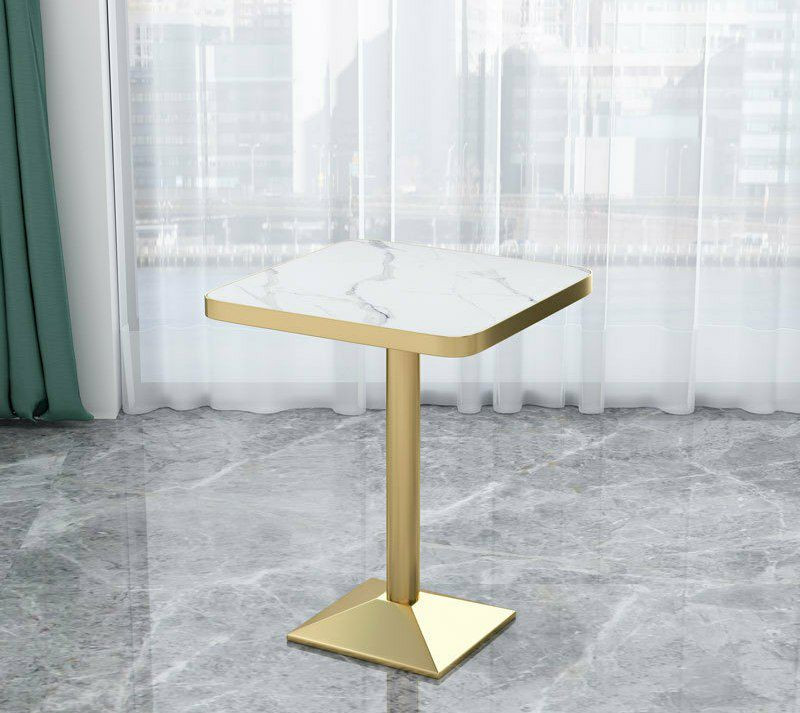 Table ronde et carree moderne de style bistrot ou d'appoint, dotée d'un plateau effet marbre blanc et d'un pied central tubulaire avec une base évasée de couleur dorée.